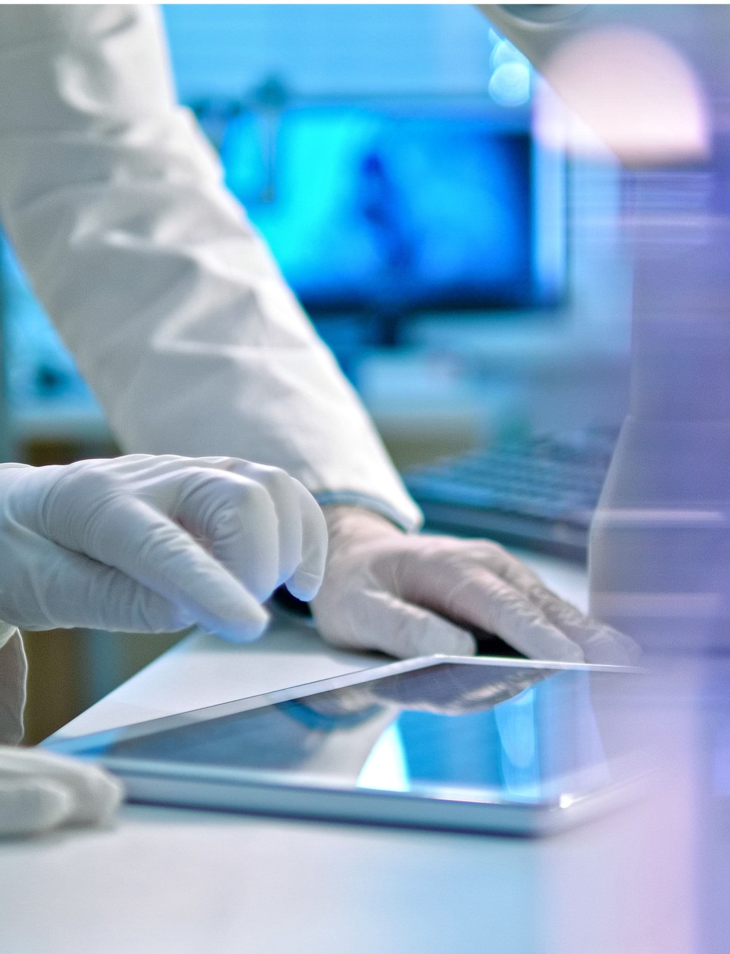Clinician in gloves reviewing oncology data on a tablet in a laboratory.